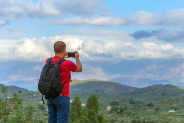Bir erkek gezgin akıllı bir telefonla Girit adasının güzel manzarasının fotoğraflarını çekiyor. Yüksek kalite fotoğraf