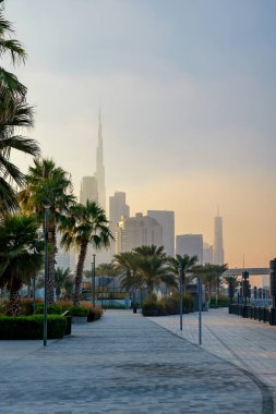  Dubai Tasarım Bölgesi 'ndeki güzel rıhtım güvertesi Dubai silueti ve Burj Halife üzerinde puslu bir günbatımı ile. Yüksek kalite fotoğraf