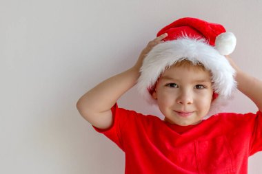 Noel kıyafetli neşeli çocuk arka planda usulca gülümsüyor, mekanı kopyalıyor. Yüksek kalite fotoğraf