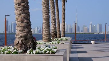 Dubai modern siluetinin arka planına sahip manzaralı deniz manzaralı gezinti alanında ikonik yüksek binalar yer alıyor. Yüksek kalite 4k görüntü