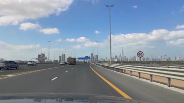 Arka planda Dubai şehir merkezinin olduğu bir yolda araba kullanmak, araba penceresinden manzara. 12 Şubat 2024, Dubai, BAE