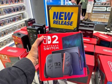 Dubai, BAE, 6 Haziran 2025. Müşteri fırlatma gününde yeni Nintendo Anahtar 2 konsolunu bir elektronik mağazasının içinde tutuyor. Yakın plan en son model paketlemeyi ve heyecanı gösterir