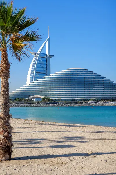 Burj Al Arab ve Jumeirah Beach Hotel Dubai, BAE plajından izlenmiş. İkonik mimari, tatil köyü lüksü ve kıyı zarafetinin yer aldığı modern bir gökyüzü.