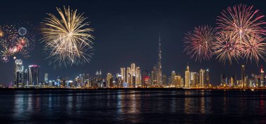 Dubai şehir merkezinin geniş panoramik gece manzarası Dubai Creek Limanı 'ndan aydınlanmış gökdelenler ve yeni yıl gökyüzünü aydınlatan şenlikli havai fişekler.