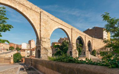 Teruel, İspanya 'da taştan bir su kemeri. Güneşli bir günde arka planda şehir binaları var..