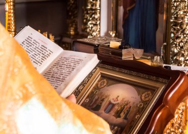 Vaftizin kutsallığı için özellikler. Yakın plan detaylar - Hıristiyan kilisesindeki vaftiz törenindeki özellikler. Kitabı papazın elleri tutuyor. Rahip İncil 'i elinde tutuyor.