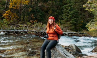 Ormanda yürüyüş yapan bir kadın. Dağ nehri manzarasından hoşlanan maceraperest kadınlar seyahat ederler. Özgürlük ve aktif yaşam tarzı kavramı. İnanılmaz soğuk bir an.