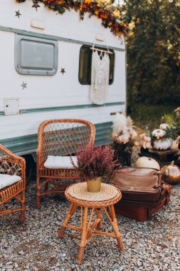 Ahşap sandalyeler ve masa kırsal kesimde sonbahar günü konforlu retro karavanın önüne kurulur.