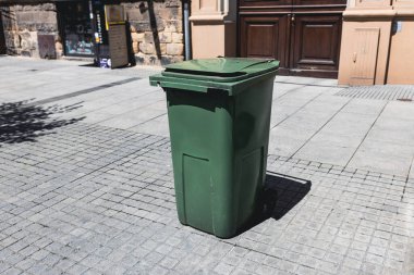 Yolun kenarındaki çöp yığını. Plastik yeşil tekerlekli çöp geri dönüşümlü çöp kutusu çöp toplama için yolun kenarında.