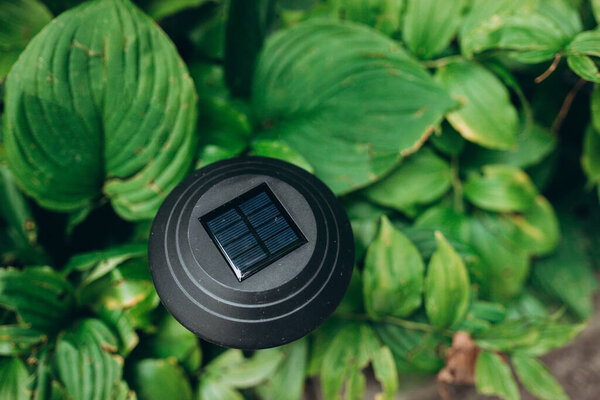 Solar powered garden flashlight. Small solar light in a flower bed. Energy saving and environmetally friendly concept.