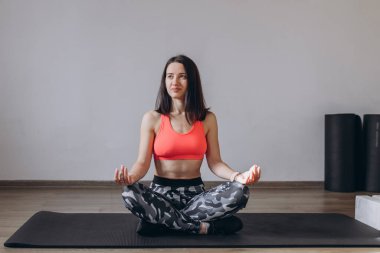 Genç ve sağlıklı bir kadın evde yoga yapıyor. Nilüfer çiçekli poz veriyor. Yoga minderinde dinleniyor. Kapalı alanda egzersiz. Spor ve sağlıklı aktif yaşam tarzı konsepti.