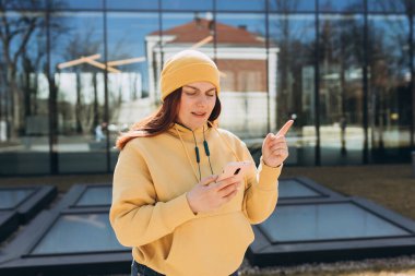 Akıllı telefon konuşmaları yapan ve şehir caddesindeki kafe terasında oturan düşünceli bir kız. Olumsuz duygular. Telefon ile şehir geçmişini gösteren bir kadın..
