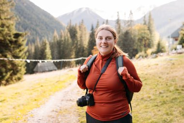 Sonbahar ormanlarında tek başına yürüyüş yapan turist kadın. Aktif yürüyüş kıyafetleri içinde mutlu kızıl saçlı insan doğanın gerisinde yürüyor..