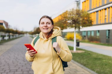 Sokakta cep telefonuyla sohbet eden genç bir kadının görüntüsü. Sırt çantalı genç kadınlar şehirde akıllı telefon kullanıyorlar..