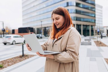 Kafkas iş kadını dışarıda dizüstü bilgisayarla poz veriyor. Dizüstü bilgisayarda başarılı bir kadın. Açık ofis. İş konsepti..