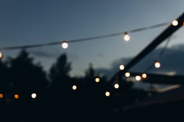 Gece vakti dekoratif dış mekan sicim lambaları, Odaklanamayan Arkaplan, Gece Şehir arkaplanı, Sarı bokeh toplarıyla parti zamanı