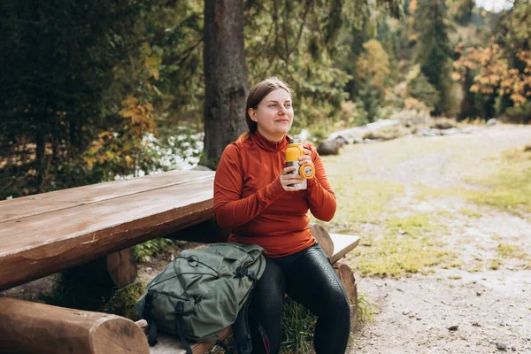 Stock image Happy redhead Woman in active trekking clothes having a halt after hiking. Hiker drinking water from water bottle or hot drink from thermos