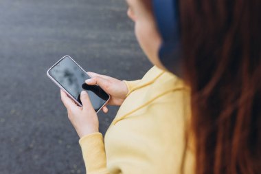 Sabahları kulaklıkla müzik dinleyen bir kadın. Akıllı telefon, arama ya da sosyal ağ konsepti kullanan ellerin yakın plan görüntüsü, hipster bir mesaj yazıyor. Grafik görüntüleme montajı için