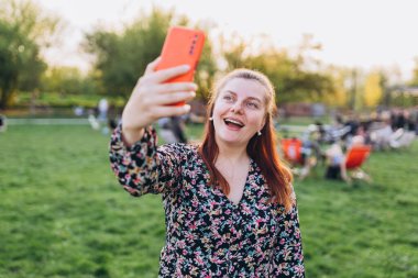 Şehir caddesinde telefonunu kullanan günlük kıyafetli güzel bir kadın. Genç hippi doğada selfie çekiyor..