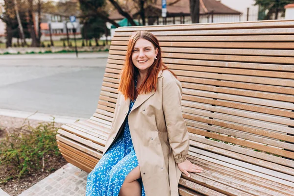 stock image Happy cheerful young woman looking at camera and sitiing on the bench in the park on city street, Urban lifestyle concept.