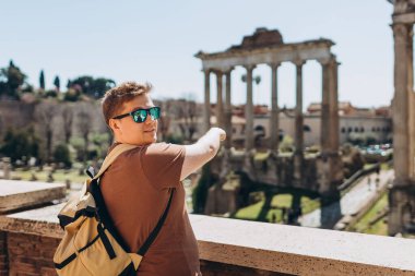 Genç turist Roma Forum 'unda dinleniyor. İtalya 'nın panoramik bakış açısından tarihsel Foro Romano imparatorluğu. Seyahat, turizm ve tatil kavramı.