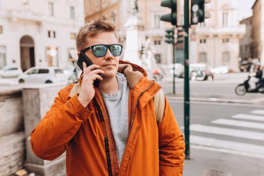 Şehir caddesinden akıllı telefonlu mutlu genç bir adam arıyor. Teknoloji, iletişim ve insan kavramı