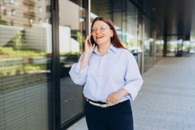 Cep telefonuyla konuşan, telefonla konuşan ve modern şehir caddesinde ayakta duran şık bir iş kadınının hayat tarzı portresi. Başarılı küçük işletmeler.