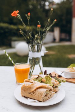 Lezzetli baget sandviç ve taze portakal suyu caddedeki kafe terasında mermer masada..
