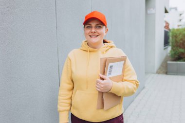 Paketi elinde olan teslimatçı kadın internet üzerinden alışveriş yaptığı için evin önündeki müşterilere paket gönderiyor. Kurye varış noktasına bir paket gönder.