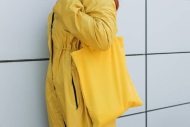 Model, sokak modasında çevreyi korumak için boş sarı kumaş çanta bulundurur. Eko Doğa Dostane Tarzı.
