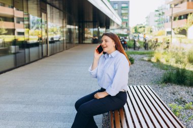 Sokakta telefonla konuşan bir kadının açık hava moda portresi. Açık havada akıllı telefon kullanan bir kadına yakın dur..