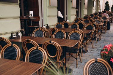 Masaları ve sandalyeleri olan boş bir restoran yaz terası. Dışarıdaki terasta müşterileri bekleyen restoran masaları..