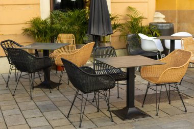 Masaları ve sandalyeleri olan boş bir restoran yaz terası. Dışarıdaki terasta müşterileri bekleyen restoran masaları..
