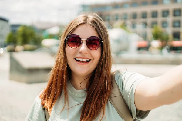 Fotoğraf gevşetici, çekici, pozitif kadın kamerayı tut ve şehir merkezinde yaz aylarında selfie çek.