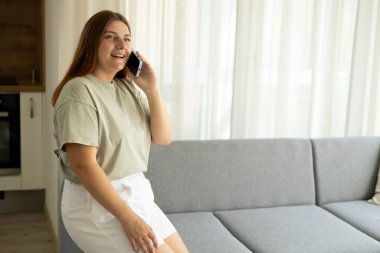 Mutlu genç bir kadın telefonda konuşur, dinler, evde oturur, evde kanepede oturur. Kanepede dinlenirken kadınsı dedikodular.