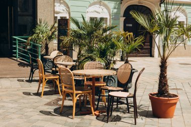 Masaları ve sandalyeleri olan boş bir restoran yaz terası. Dışarıdaki terasta müşterileri bekleyen restoran masaları..