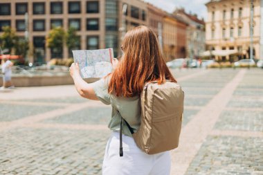 Haritalı mutlu turist kız Avrupa 'ya seyahat ediyor. Seyahat etmek için ilginç yerleri keşfederek tatil kavramı. Kızıl Saçlı Kadın Konumları Arıyor