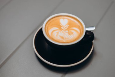 Gri metal masa arkaplanlı bir fincan taze kapuçino. Kahve bağımlılığı konsepti. Sıcak içecek.