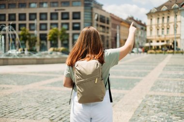 Çekici genç bayan turist yeni şehri keşfediyor. Sıcak ve güneşli bir günde kızıl saçlı kadın işaret ediyor. Şehir yaşam tarzı konsepti. Gezgin