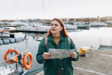 Şehir haritasına bakan kafası karışmış gezgin kayboldu. Üzgün bayan kayboldu, Gdansk haritasını kontrol ediyor. İlkbaharda Avrupa 'yı geziyorum. Haritalı bir kadın deniz kenarında yürüyor..