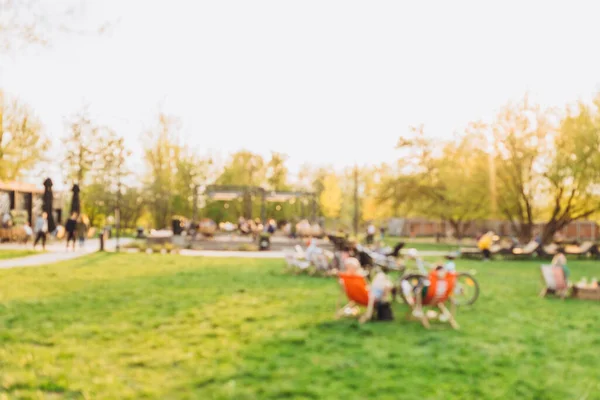 Blurred garden with lighting sunset. Public park with people. Blurred image of people in day in city park background