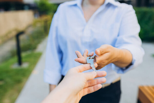 Агент по недвижимости дает ключи от дома женщине. Закрыть женскую руку и забрать ключи от дома у риэлтора. Ипотека на приобретение квартиры, получение доступа к собственному дому