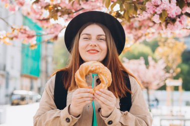 Çekici genç bayan turist Krakow 'da geleneksel Polonya usulü simit tutuyor. İlkbaharda Avrupa 'yı geziyorum. Seçici odaklanma. Yüksek kalite fotoğraf