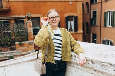 Roma 'daki İspanyol merdivenlerinde poz veren mutlu, genç, çekici sarışın kadın. Kameraya bakan güzel kadınların yakın plan portresi. 30 'ların kızı ılık bir bahar gününde şehir caddesinde yürüyor..