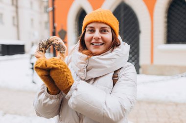 Sarı şapkalı çekici genç bayan turist elinde simit tutuyor. Krakow 'daki Pazar Meydanı' nda geleneksel Polonya simitli simit. Kış zamanında Avrupa 'yı gezmek.