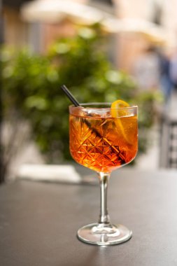 Aperol Spritz Kokteyli. Açık havada buz küpleri ve portakallı masaya dayalı alkollü içecek. İtalya 'da masaya portakal dilimi ve saman kokteyle servis edilmiş.