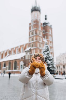 Sarı şapkalı çekici genç bayan turist elinde simit tutuyor. Krakow 'daki Pazar Meydanı' nda geleneksel Polonya simitli simit. Kış zamanında Avrupa 'yı gezmek.
