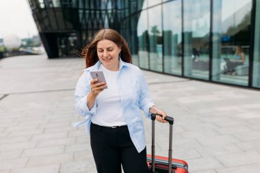 Zarif bir iş kadını havaalanının dışında bavulla yürürken cep telefonundan e-postaları kontrol ediyor. Güzel bir kadın internette akıllı telefonuyla bilgi arıyor.