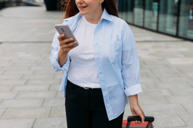 Zarif bir iş kadını havaalanının dışında bavulla yürürken cep telefonundan e-postaları kontrol ediyor. Güzel bir kadın internette akıllı telefonuyla bilgi arıyor.