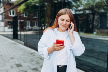 Neşeli kadın telefonlarının fotoğrafı, popüler blogcu yeni yazı yazıyor ve ikinci telefonla konuşuyor.